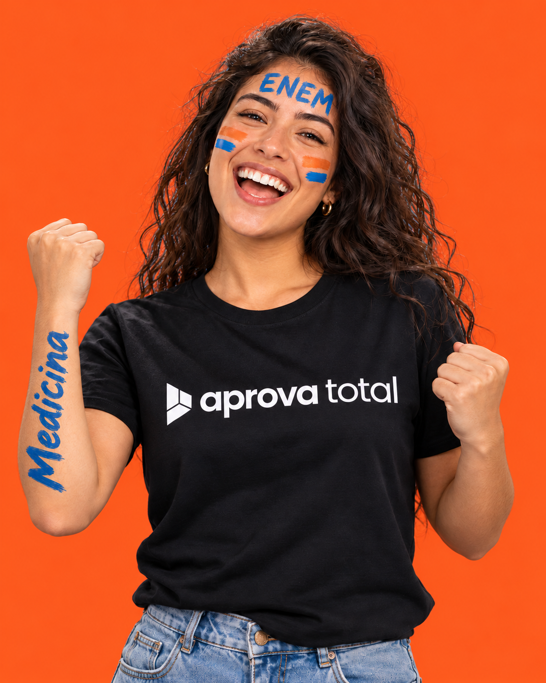 Estudante sorrindo, com pintura de comemoração no rosto e camiseta preta Aprova Total